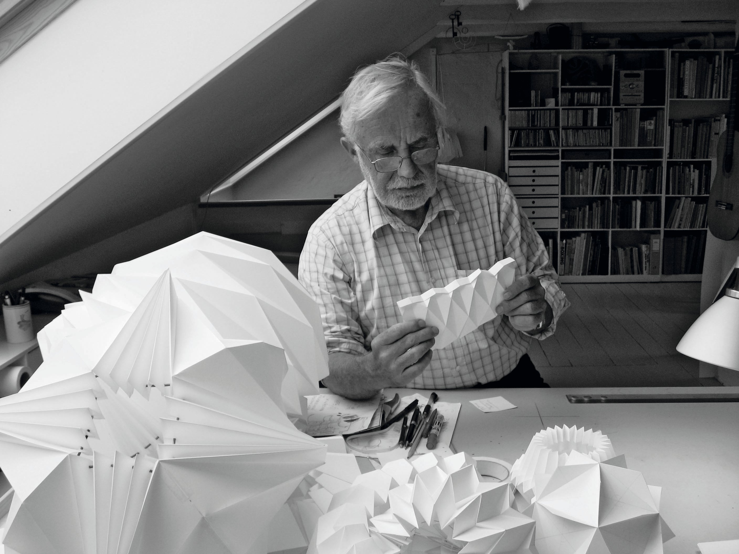 Arkitekt Andreas Andersen siddende på hans kontor med foldede design lamper omkring sig