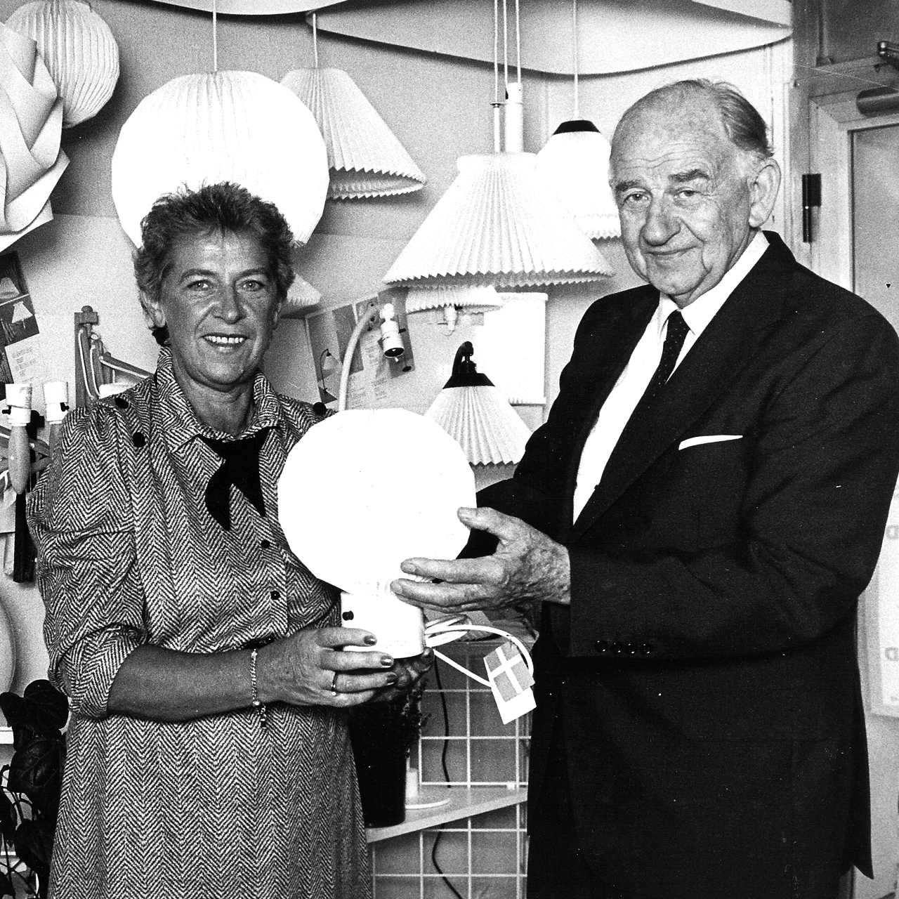 Direktør Jan Klint ved siden af en kvindelig medarbejder der holder en Le Klint bordlampe, model 375
