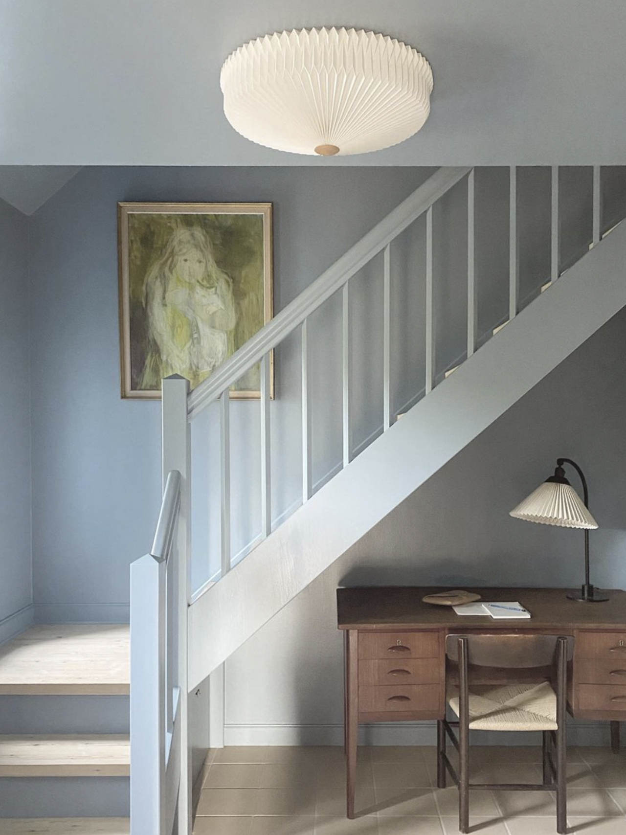 Indretning af entre med Le Klint plafond i loftet og bordlampe på et skrivebord under trappen