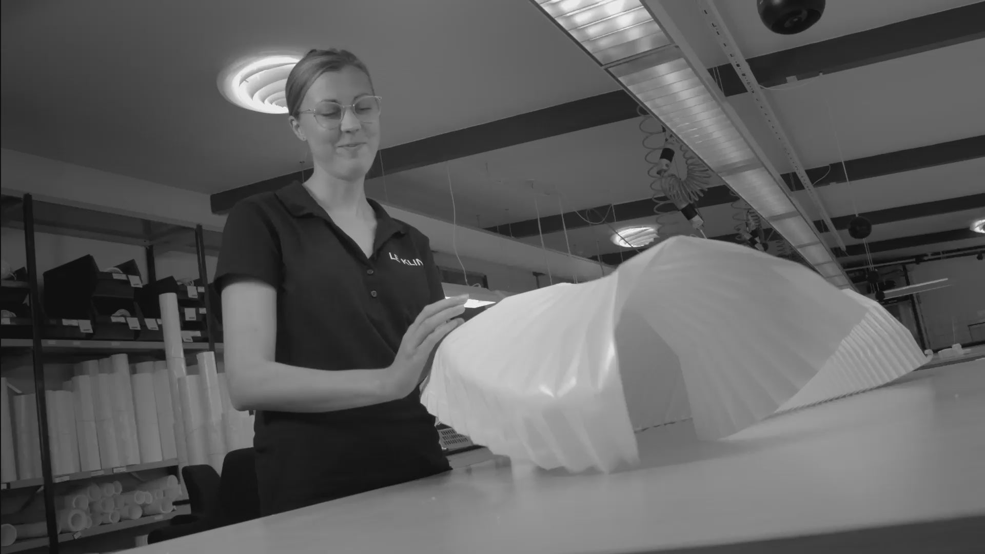 medarbejder Anna i foldestuen hos Le Klint hvor hun viser sit arbejde med håndfoldede lampeskærme